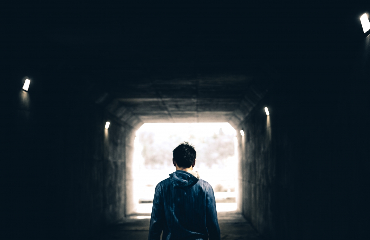 Image of young man from behind walking down a tunnel