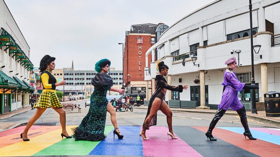 Diverse people walking across a rainbow-coloured pedestrian crossing