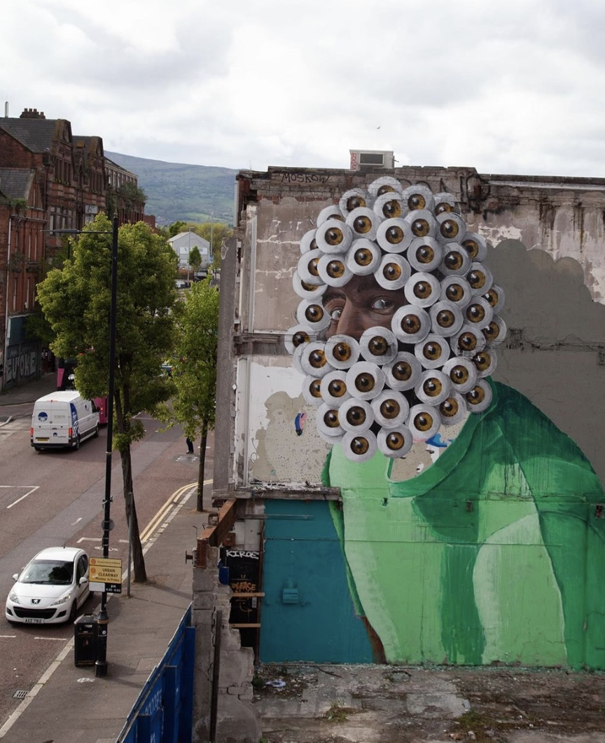 Mural of face with hundreds of eyeballs on wall in Belfast City Centre.